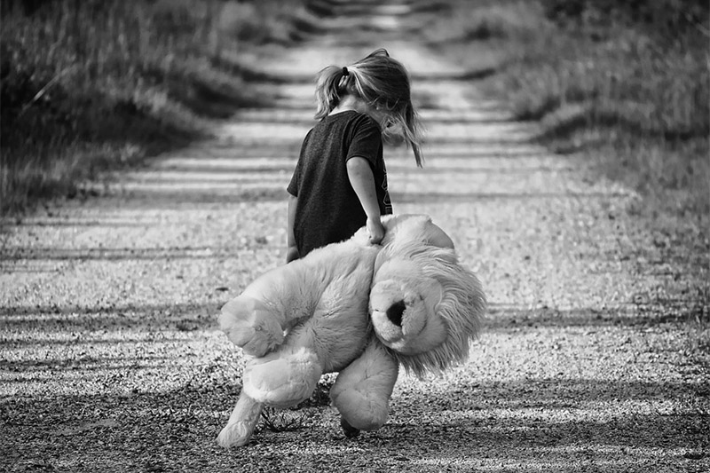 Sad girl, walking away with her teddy bear