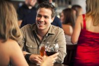 Guy smiling at his date, at a bar; Dating