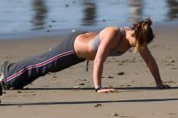 Woman doing push-up at a beach: Discipline